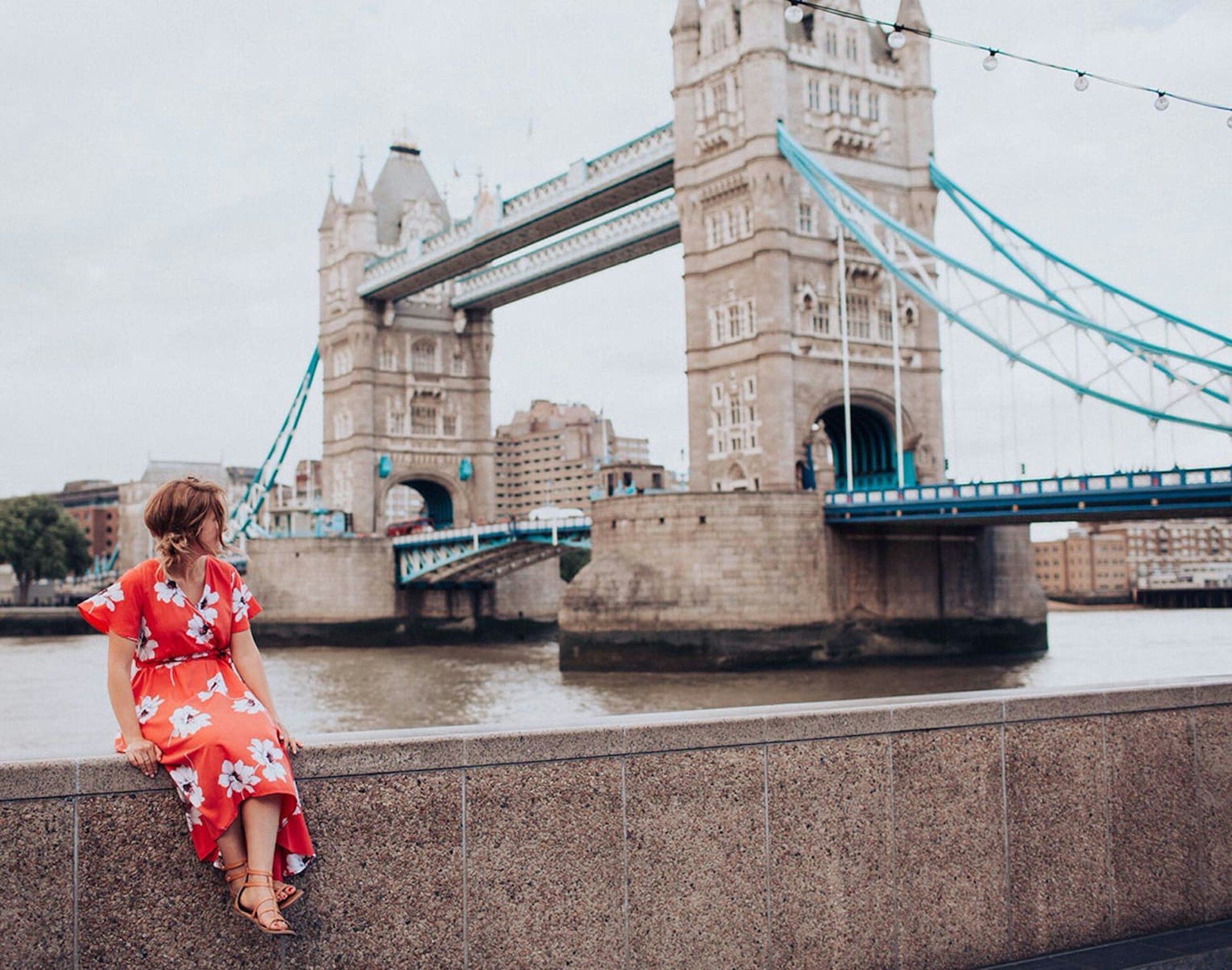 Woman sat on railings near London Tower Bridge