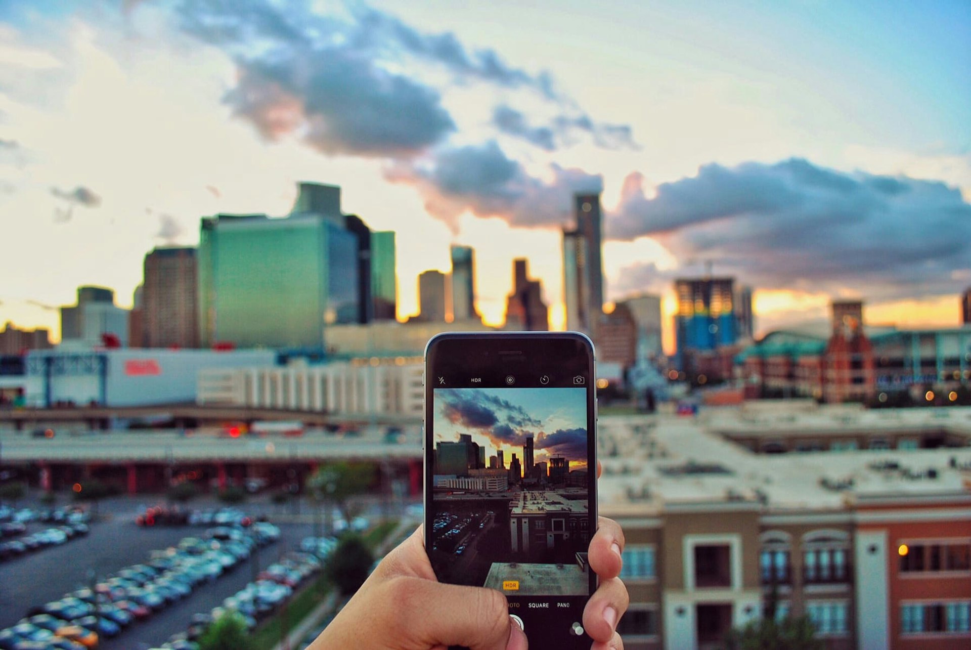 Person taking phone camera photo of skyline in Houston, Texas at sunset