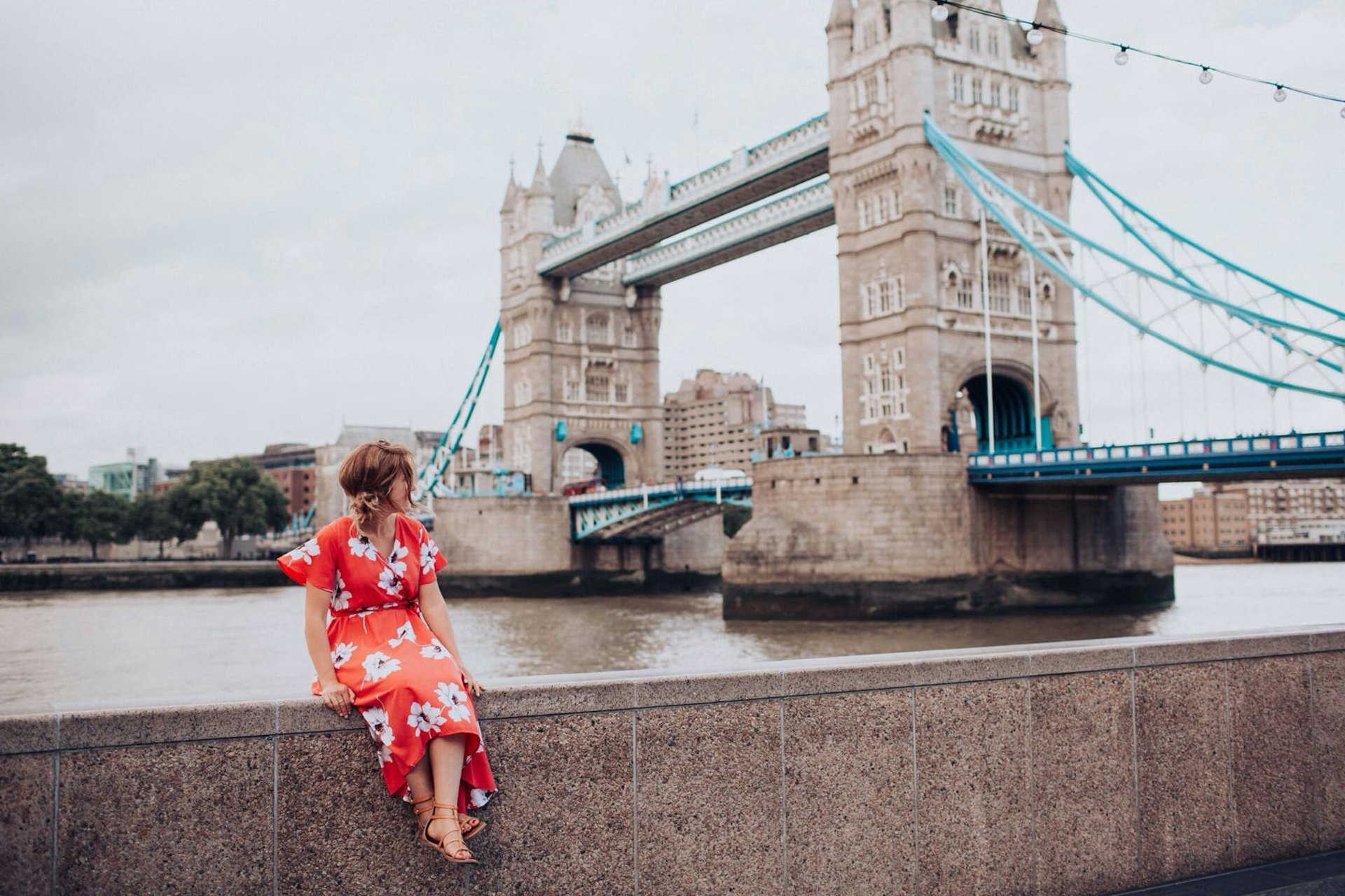 Woman sat on railings near London Tower Bridge
