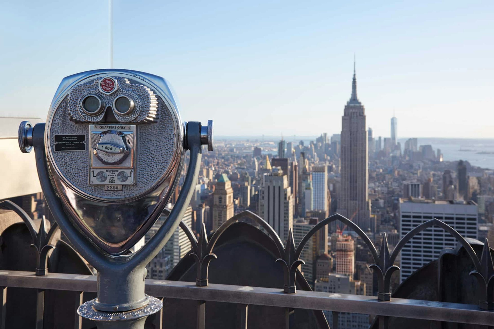 Binoculars on Rockefeller Center with Empire State Building and city view at the end of the day in New York